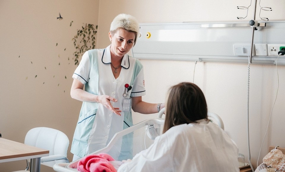 Porodní asistentka při návštěvě ženy na lůžku
